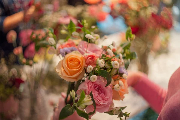 Workshop fiorista, rendendo mazzi di fiori e composizioni floreali. Donna che raccoglie un mazzo di rose. Concentrazione morbida — Foto Stock