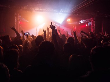 Rock konseri, eller yukarı, kırmızı sesi yükselterek mutlu insan siluetleri