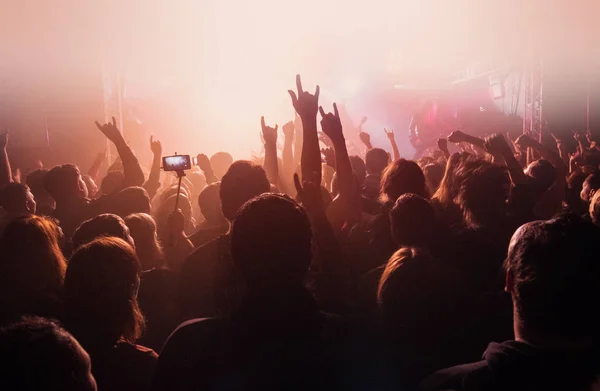 Koncert rockowy, sylwetki szczęśliwych ludzi, podnosząc ręce, czerwony odcień — Zdjęcie stockowe
