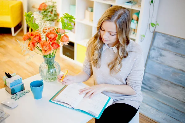 Joven empresaria sentada en el escritorio y trabajando. Hermosa mujer llena planificador — Foto de Stock