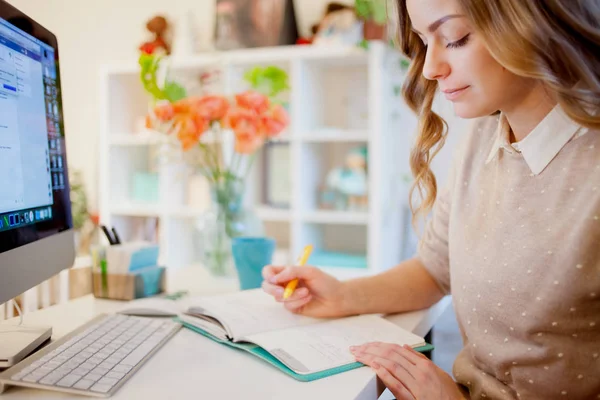 Jeune femme d'affaires assise au bureau et travaillant. Belle femme remplit planificateur — Photo