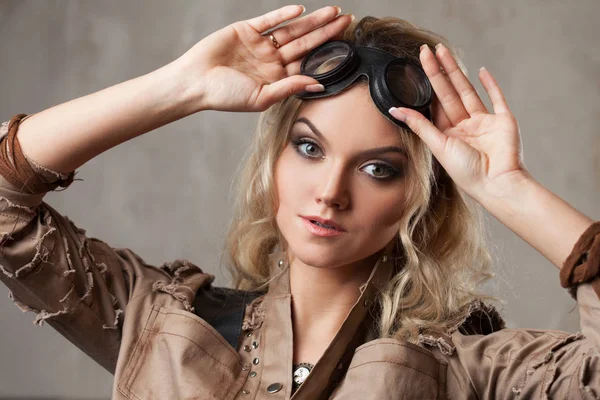 Retrato de una hermosa mujer steampunk en gafas Aviator sobre fondo gris. Mirando hacia arriba — Foto de Stock