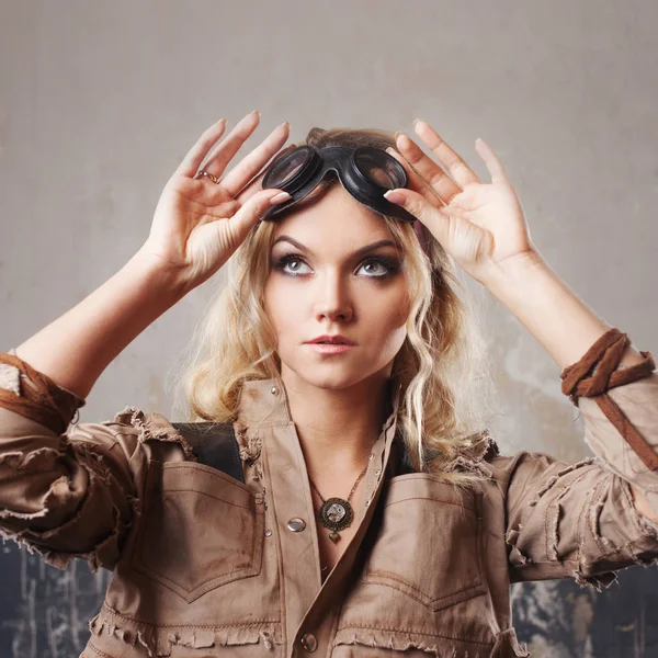 Retrato de una hermosa mujer steampunk en gafas Aviator sobre fondo gris. Mirando hacia arriba — Foto de Stock