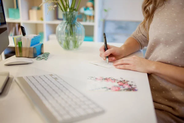 Primo piano di una mano femminile firmare la cartolina a mano in ufficio — Foto Stock