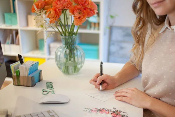 Gros plan d'une femme mains signer la carte postale à la main dans le bureau — Photo