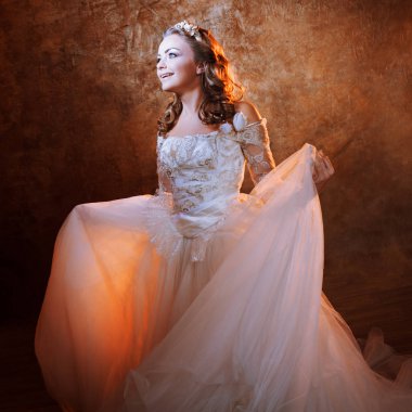 Güzel mutlu dans eden gelin lüks gelinlik, portre dokulu arka plan üzerinde altın tonlarda