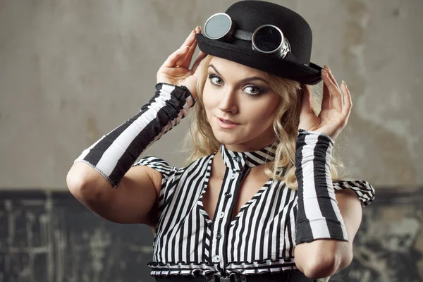 Porträtt av en steampunk kvinna i hatt-plommonstop med skyddsglasögon, över grunge bakgrund. Vackra lady i viktoriansk stil — Stockfoto