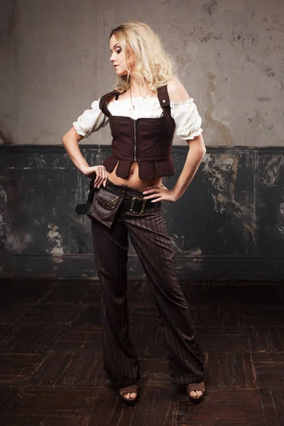 Portretul unei femei frumoase steampunk într-un costum de pantaloni cu vestă, peste fundal grunge . — Fotografie, imagine de stoc