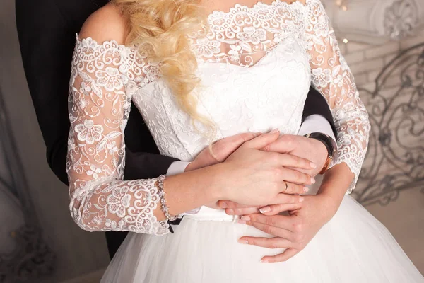 Bruidegom omhelst bruid van achteren. Trouwjurk. Close-up van de handen. — Stockfoto