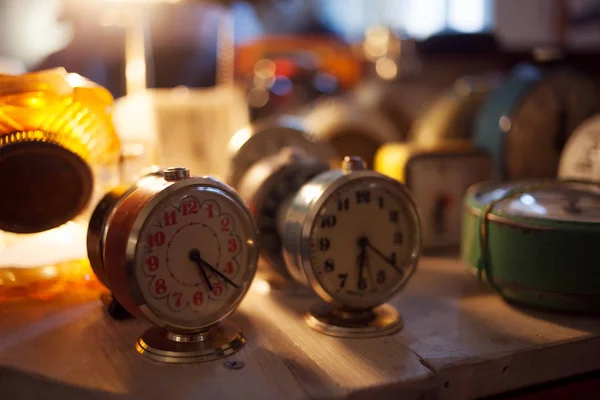 Bodegón, despertador de horas en la mesa. Muchas alarmas diferentes, una pequeña profundidad de campo — Foto de Stock