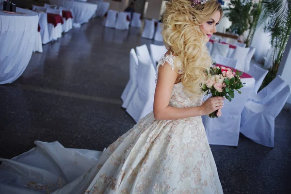 Jonge bruid met perfecte huid mode en make-up, krullend haar, bloemen en tiara op het hoofd, binnenshuis — Stockfoto