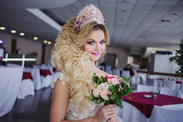 Novia de moda joven con piel y maquillaje perfectos, pelo rizado, flores y tiara en la cabeza, en interiores —  Fotos de Stock