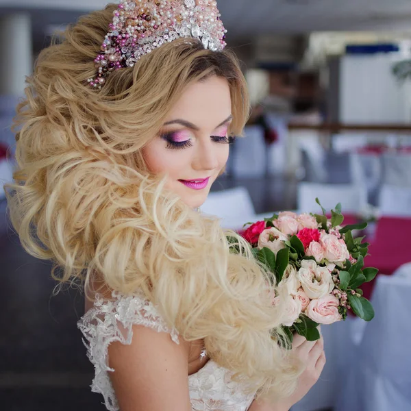 Giovane sposa di moda con pelle perfetta e trucco, capelli ricci, fiori e tiara sulla testa, all'interno — Foto Stock