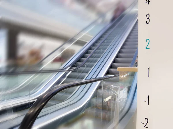 Rolltreppe im modernen Einkaufszentrum, Seitenansicht. Werbetafel mit Fußböden auf der rechten Seite — Stockfoto