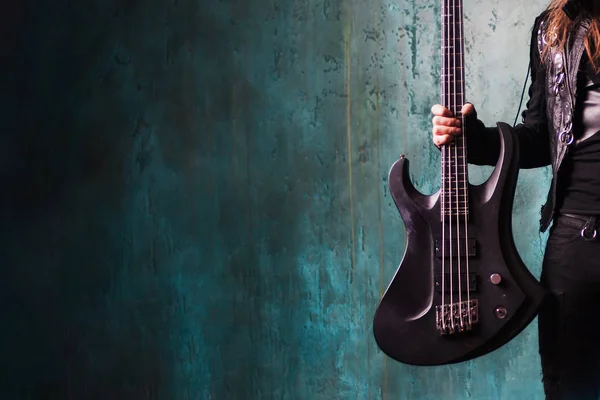 Man in black leather holding a guitar. Rocker and metalhead, youth style, music. Textured background, place for text — Stock Photo, Image