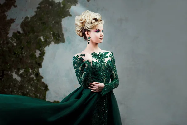 Portré, fiatal vonzó szőke nő, egy gyönyörű zöld ruhát. Textúrázott háttérre, belső. Luxus frizura — Stock Fotó