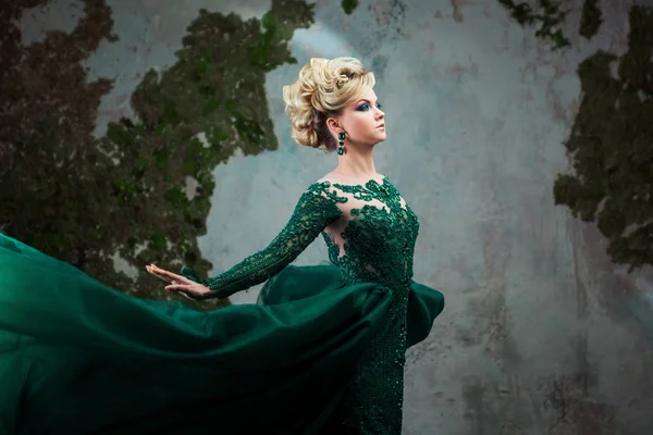 美しい緑のドレスで若い魅力的なブロンドの女性の肖像画。テクスチャ背景、インテリア。豪華な髪型 — ストック写真