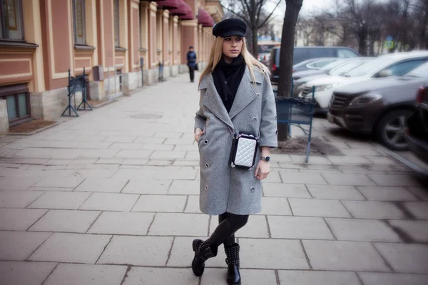 Unga, trendiga och attraktiva blondin promenader runt staden, flicka i en snygg hatt och en grå kappa — Stockfoto