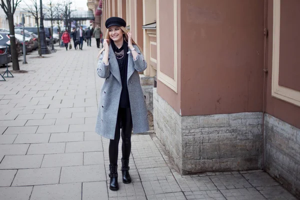 Jeune, hanche et jolie blonde se promène dans la ville, fille dans un chapeau élégant et un manteau gris — Photo