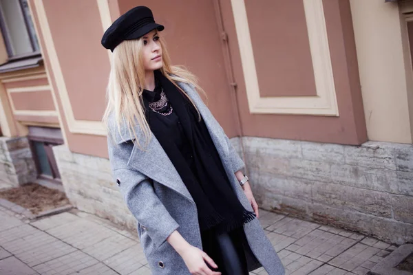 Young, hip and attractive blonde walking around the city, girl in a stylish hat and a gray coat — Stock Photo, Image