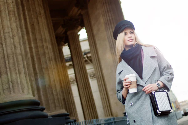 Gitmek için kız şık bir şapka ve gri bir ceket kahve ile şehir dolaşan genç, kalça ve çekici sarışın — Stok fotoğraf