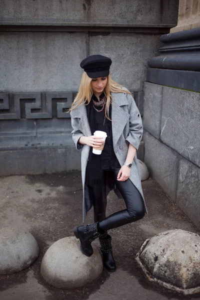 Joven, cadera y atractiva rubia paseando por la ciudad con café para llevar, chica con un sombrero elegante y un abrigo gris —  Fotos de Stock