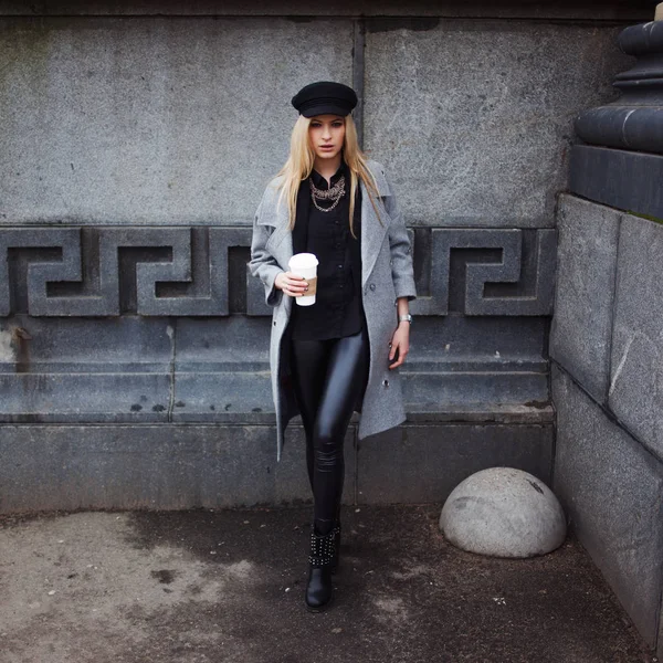 Jeune, branchée et jolie blonde se promène dans la ville avec du café à emporter, fille au chapeau élégant et manteau gris — Photo
