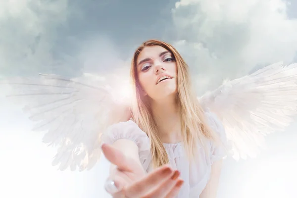 An angel from heaven gives you a hand. Young, wonderful blonde girl in the image of an angel with white wings. — Stock Photo, Image