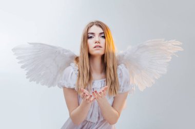 Bir şey avucunda tutan gökten bir melek. Beyaz kanatlı bir melek görüntüsündeki genç, harika sarışın kız.