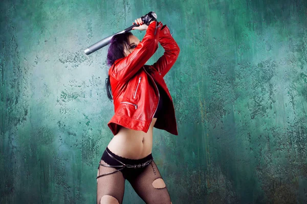 Aggressive punk woman strike someone with a bat, in red leather jacket — Stock Photo, Image