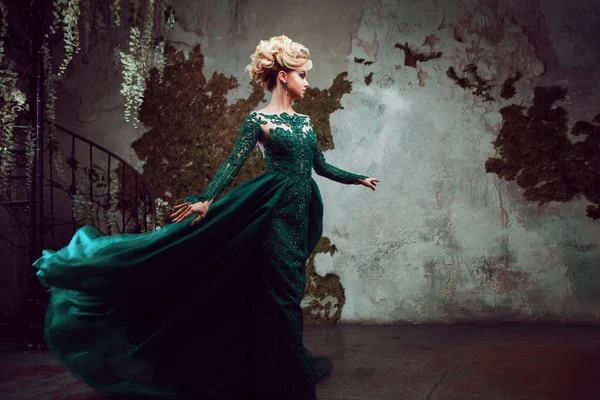 美しい緑のドレスで若い魅力的なブロンドの女性の肖像画。テクスチャ背景、インテリア。豪華な髪型 — ストック写真