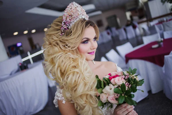 Jonge bruid met perfecte huid mode en make-up, krullend haar, bloemen en tiara op het hoofd, binnenshuis — Stockfoto