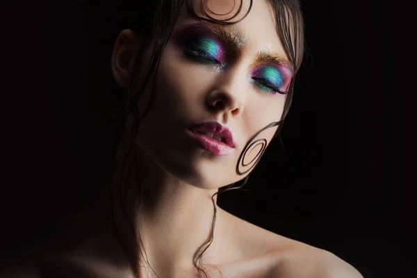 De lichte make-up jong mooi meisje met een natte look shine, donkere achtergrond, donkere, mysterieuze silhouet in de schaduw — Stockfoto