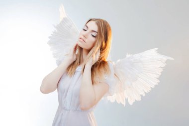 Gökten bir melek. Beyaz kanatlı bir melek görüntüsündeki genç, harika sarışın kız.