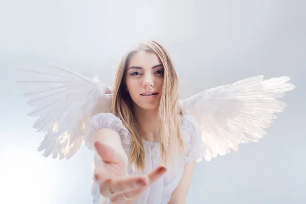 Ангел с небес протягивает тебе руку. Молодая, прекрасная блондинка в образе ангела с белыми крыльями . — стоковое фото