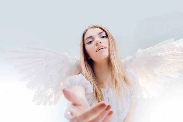 An angel from heaven gives you a hand. Young, wonderful blonde girl in the image of an angel with white wings. — Stock Photo, Image