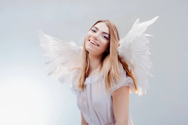 Um anjo do céu. Jovem, menina loira maravilhosa na imagem de um anjo com asas brancas . — Fotografia de Stock