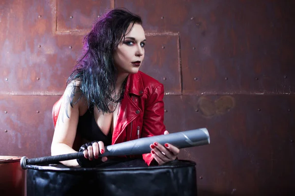 Mulher punk agressivo com um morcego, em jaqueta de couro vermelho — Fotografia de Stock