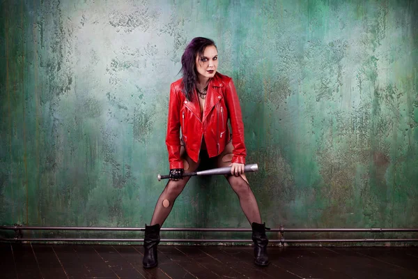 Mujer punk con un murciélago en chaqueta de cuero rojo, de pie contra la pared —  Fotos de Stock
