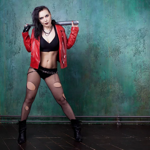 Punk donna con un pipistrello in giacca di pelle rossa, in piedi contro il muro — Foto Stock