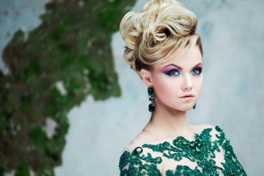 Güzel yeşil giysili genç çekici sarışın kadın portresi. Dokulu arka plan, iç. Lüks saç modeli