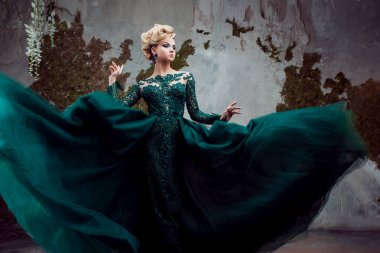 Güzel yeşil giysili genç çekici sarışın kadın portresi. Dokulu arka plan, iç. Lüks saç modeli