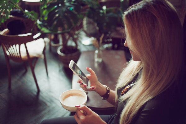 Молодая женщина фрилансер болтает по мобильному телефону, сидя на диване в винтажном кафе
