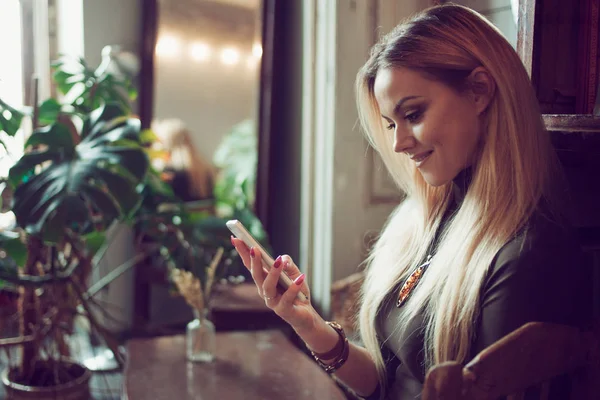 Fiatal női szabadúszó mobiltelefon közben ül a kanapén, vintage kávézóban beszélget — Stock Fotó