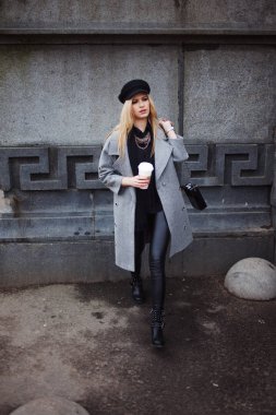 Gitmek için kız şık bir şapka ve gri bir ceket kahve ile şehir dolaşan genç, kalça ve çekici sarışın