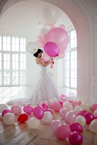 Mujer joven en vestido de novia en el interior de lujo con una masa de globos de color rosa y blanco . —  Fotos de Stock