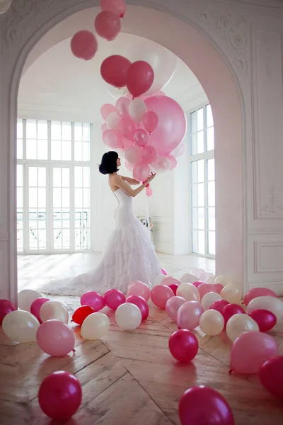 Mujer joven en vestido de novia en el interior de lujo con una masa de globos de color rosa y blanco . — Foto de Stock