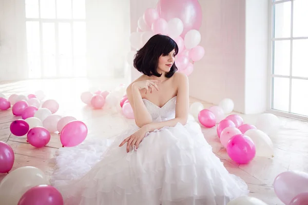 Mujer joven en vestido de novia en el interior de lujo con una masa de globos de color rosa y blanco . — Foto de Stock