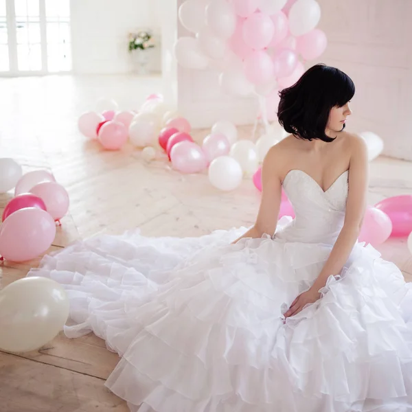 Mujer joven en vestido de novia en el interior de lujo con una masa de globos de color rosa y blanco . — Foto de Stock