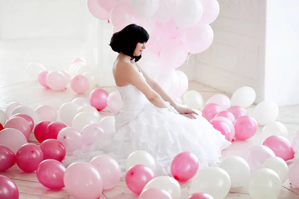 Mujer joven en vestido de novia en el interior de lujo con una masa de globos de color rosa y blanco . — Foto de Stock